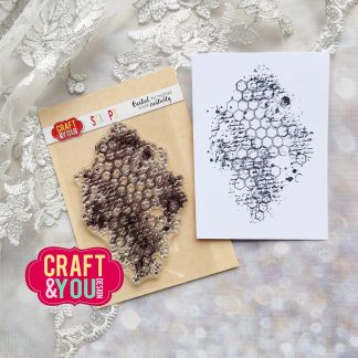Hexagonal honeycomb stamp set on kraft backing with inked impression, placed beside a white card with a hexagon pattern on a lace backdrop.